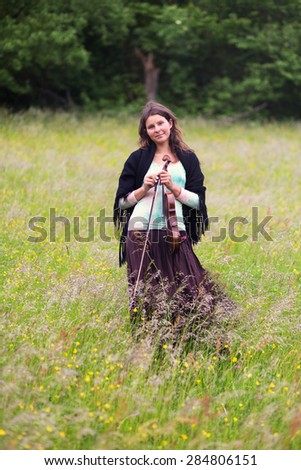 violinist on a meadow full of flowers, Young girl playing music instrument