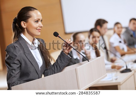 Businesswoman standing on stage and reporting for audience Royalty-Free Stock Photo #284835587