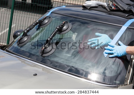 Glazier removing windshield or windscreen on a car Royalty-Free Stock Photo #284837444