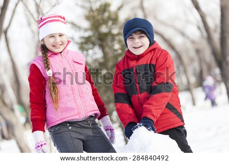 Cute boy and girl building snowman in winter park