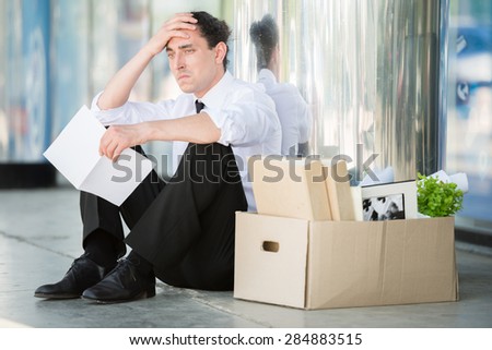 Fired frustrated man in suit sitting near office. Royalty-Free Stock Photo #284883515