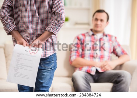 Boy hiding behind the back bad test result. Royalty-Free Stock Photo #284884724