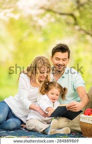 Image of happy young family having picnic outdoors.