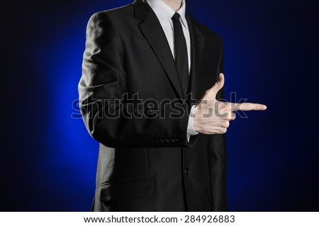 Business and the presentation of the theme: man in a black suit showing hand gestures on a dark blue background in studio isolated