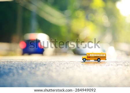 Yellow school bus toy model the road crossing.Shallow depth of field composition and  afternoon scene.