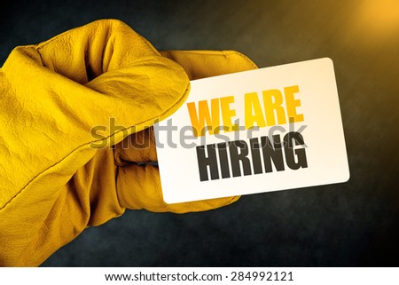 We Are Hiring on Business Card, Male Hand in Yellow Leather Construction Working Protective Gloves Holding Card with Rounded Corners.