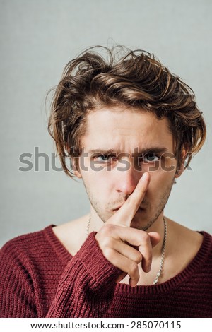Man shows gesture quieter. On a gray background.