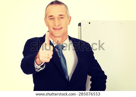 Mature businessman with ok sign near flip chart