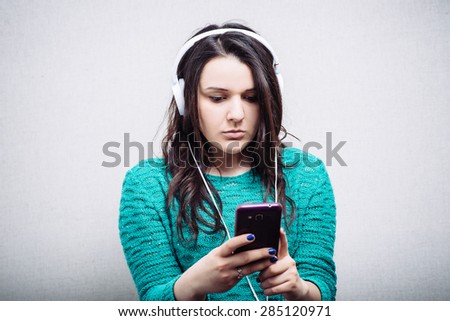Girl listening to music on headphones with the phone