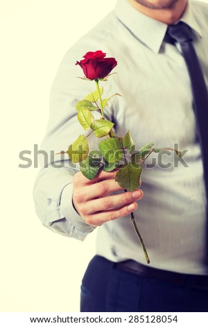 Young handsome man holding red rose.