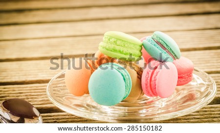 Colorful macarons on the wooden background with vintage pastel style soft focus.