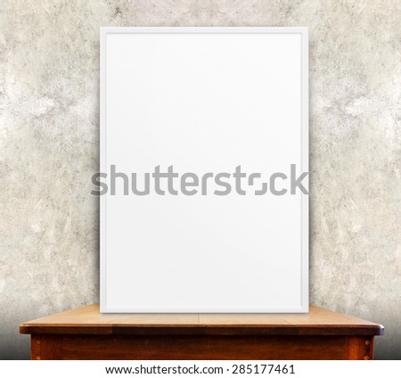 Empty white frame on wooden table at grunge concrete wall in background,Mock up for adding your design,