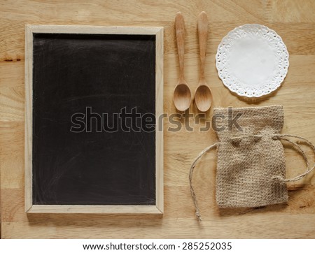 Burlap bag and blackboard with wooden spoon set. Object put on surface wood table. Image retro filter effect. Brown tone.