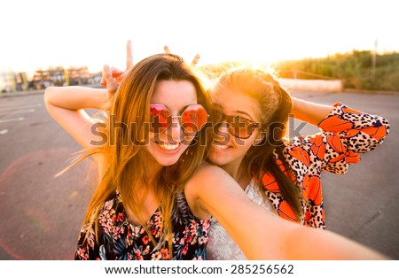 Selfie fun girls taking picture at cool sunset.Summer holidays, girls at smartphone camera taking self-portrait on their travel vacations.Best friends girls make picture at sunset,camera selfie pic