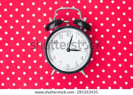Retro alarm clock on red polka dot background