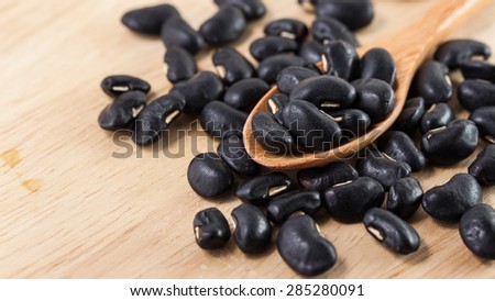 Black beans on a wooden spoon on a table