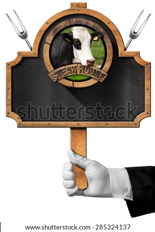 Steak House / Hand of waiter holding a empty blackboard with symbol of a steak house with head of cow and two forks. Isolated on white background