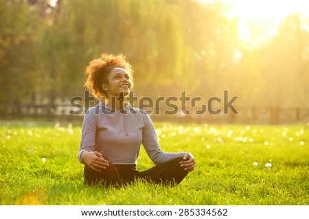 Happy young woman sitting outdoors in yoga position Royalty-Free Stock Photo #285334562