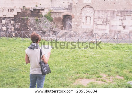 Tourist with map getting around ancient roman ruins in Rome old town, heritage of early italian history, now famous travel destination for tourists. Marsala toned image, decontrasted.