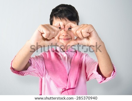 Boy making a heart with his hands over textured background