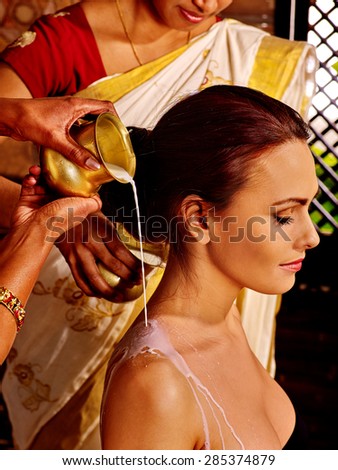 Woman having Pouring milk in Indian spa treatment salon. 