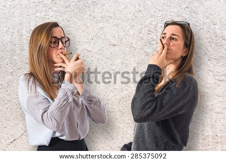 Twin sisters smoking over textured background