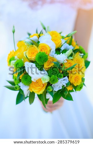 bride holds a wedding bouquet,  yellow roses