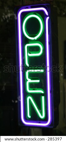 A neon OPEN sign lit up in the front window of a store.