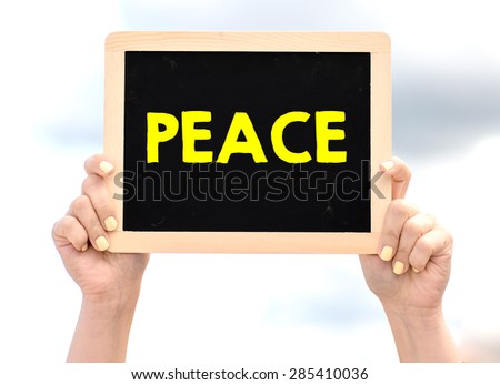 Hands holding blackboard with peace