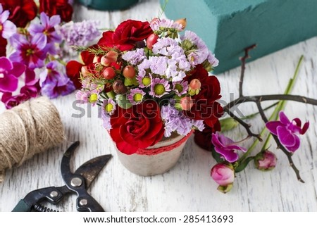 Florist workplace: Floral arrangement with red carnations and hypericum seeds, copy space