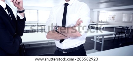 Smiling businessman with arms crossed against empty class room