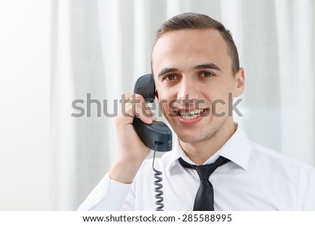 Smiling businessman while communicating on phone in office