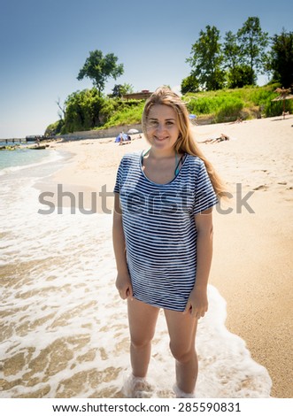 Beautiful woman in sailor shirt walking on the seashore at sunny day
