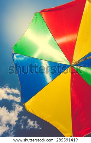 Toned photo of colorful umbrella against blue sky