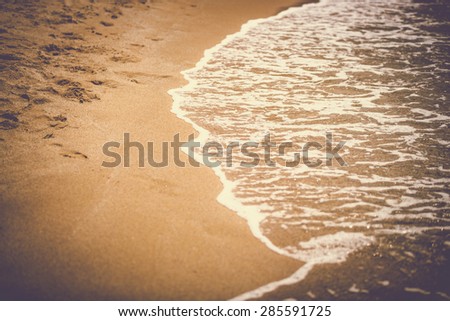 Retro toned photo of sea waves rolling on the sandy beach