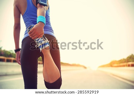 Young woman runner warming up before run on city  Royalty-Free Stock Photo #285592919