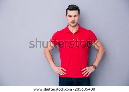 Portrait of a handsome casual man standing over gray background and looking at camera
