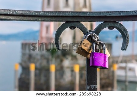 Love padlocks or love locks on a railing in the harbor of Lindau on blurred lighthouse background