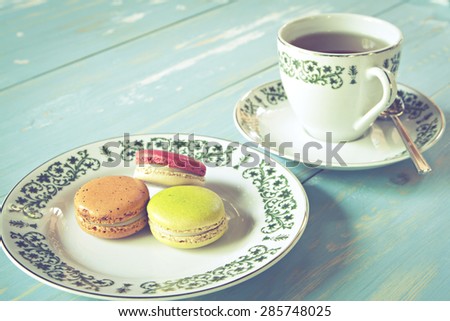Macarons with a cup of tea on wooden table. Vintage style. 