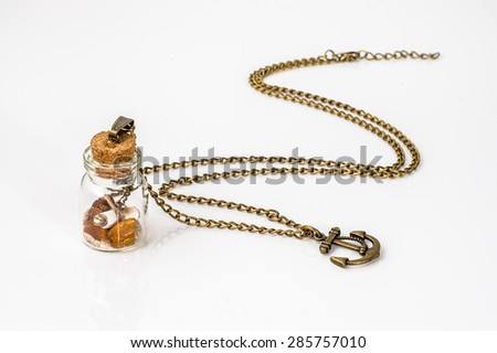 Pendant made with glass bottle, antique gold chain and amber isolated on white background. Handmade jewelry.