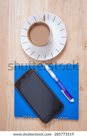 Hot coffee on the table notebooks, pens and Smartphone