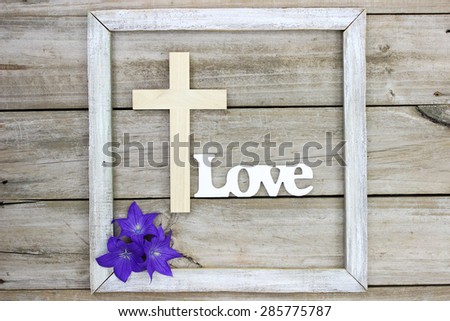 Wooden cross and purple balloon flowers by the word Love on rustic wood background; Easter, Memorial Day and religious background