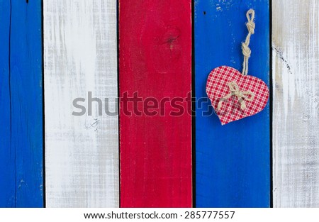 Red heart hanging on red, white and blue rustic wooden background