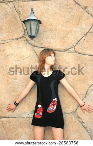 Pretty blond girl at the ancient style wall and lamp.