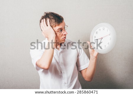 afraid man with glasses looks at the clock