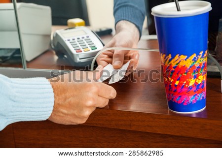 Cropped image of man buying movie tickets from seller at box office