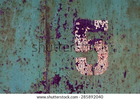 White number 5 on old painted in green and rusted metal panel 