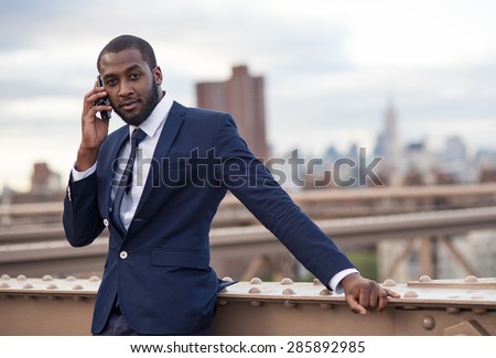 Young businessman talking at the phone on Brooklyn Bridge. New York City.