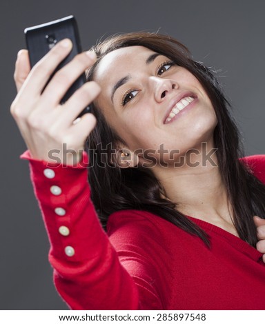 happy young woman enjoying taking photos of herself with mobile phone