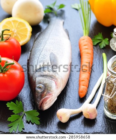 raw fish with fresh vegetables on a black background